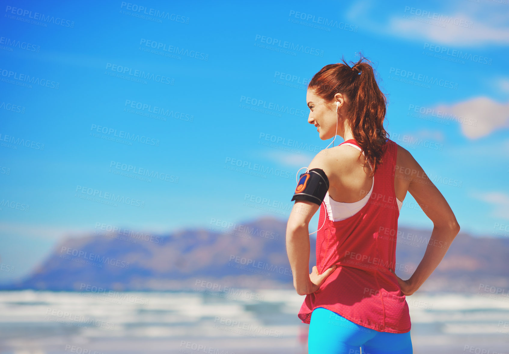 Buy stock photo Rearview shot of a young woman standing with her hands on her hips on the beach