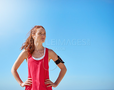 Buy stock photo Runner woman, outdoor and sky with earphones for music, workout motivation and training in summer. Young athlete girl, exercise and running for wellness by blue sky with focus, sunshine and fitness