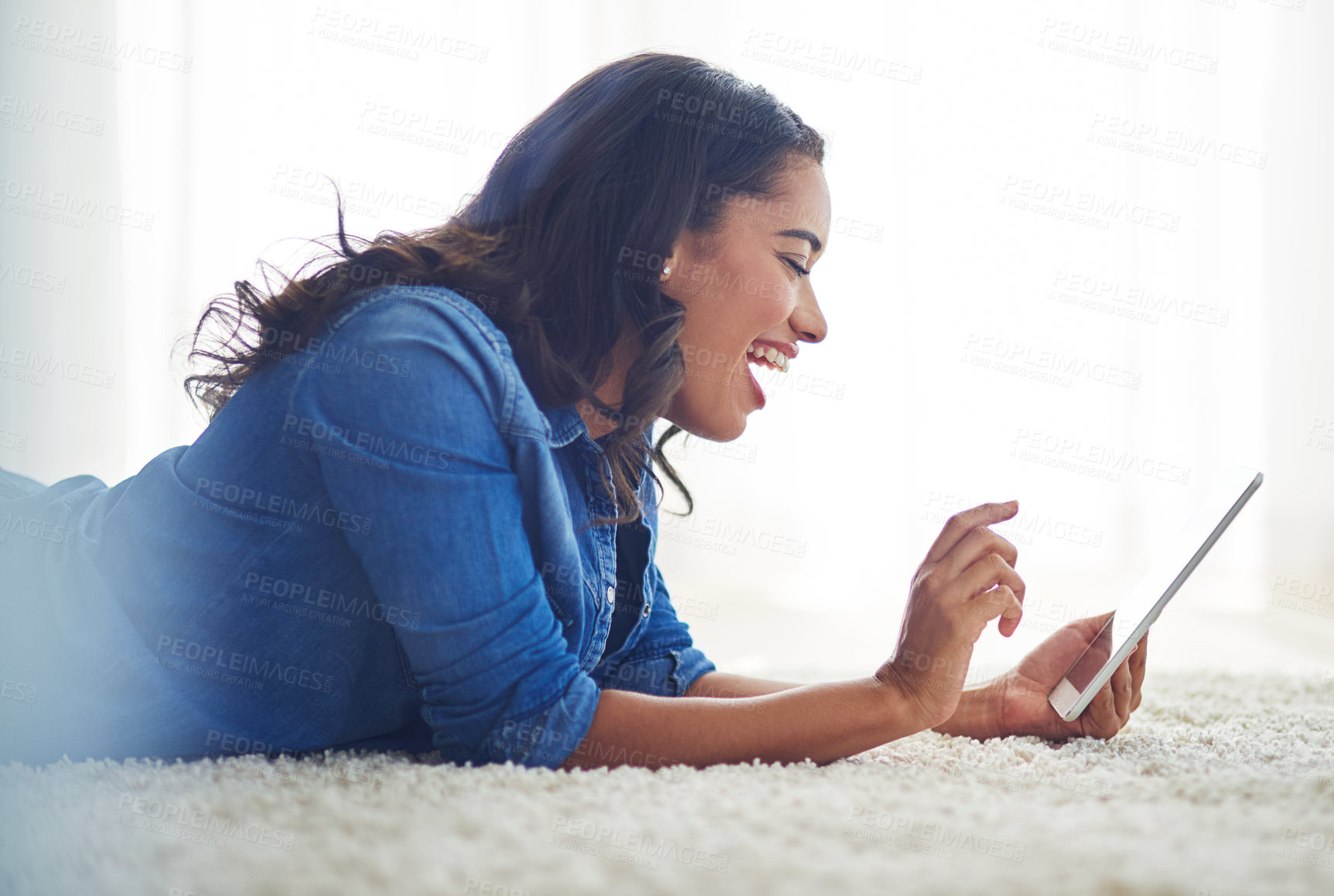 Buy stock photo Shot of a young woman browsing the web on her tablet at home