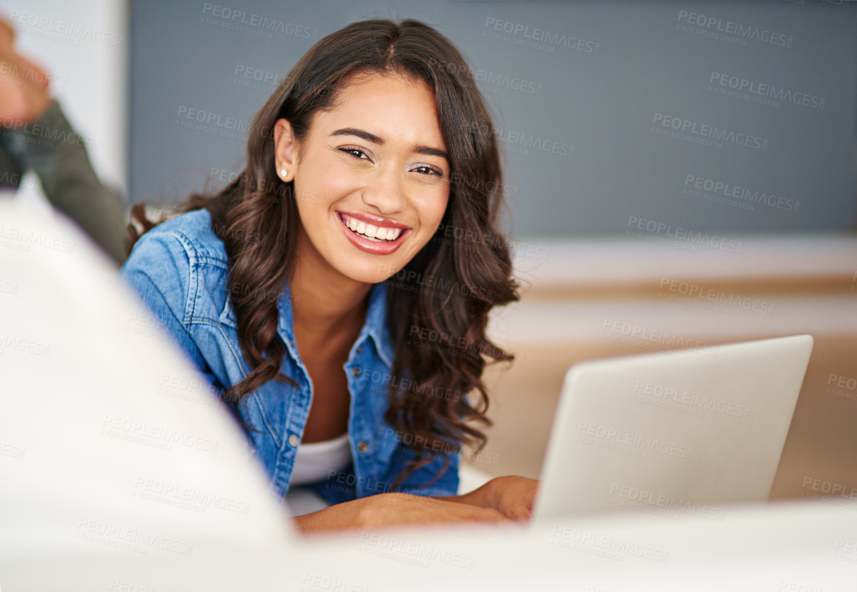 Buy stock photo Cropped portrait of an attractive young woman using her laptop while lying on the sofa
