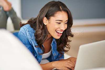 Buy stock photo Cropped shot of an attractive young woman using her laptop while lying on the sofa