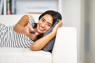 Buy stock photo Cropped portrait of a young woman watching TV while relaxing on her sofa at home