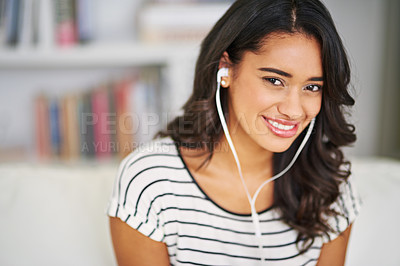 Buy stock photo Cropped portrait of a young woman listening to music while relaxing on her sofa at home