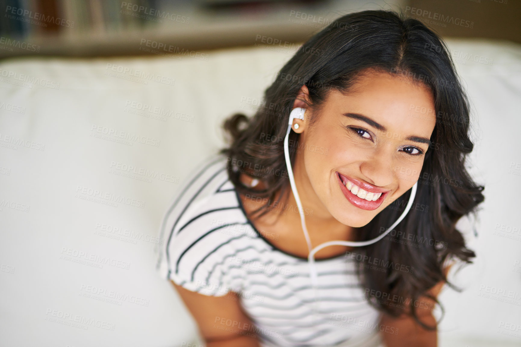 Buy stock photo Cropped portrait of a young woman listening to music while relaxing on her sofa at home