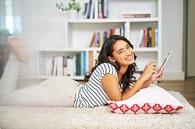 Buy stock photo Cropped portrait of a young woman using her tablet while relaxing at home