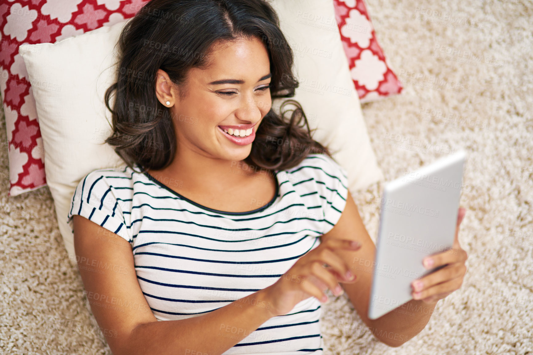 Buy stock photo High angle shot of a young woman using her tablet while relaxing at home