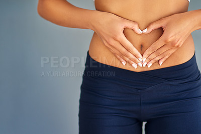 Buy stock photo Cropped shot of a young woman making a heart shape on her stomach