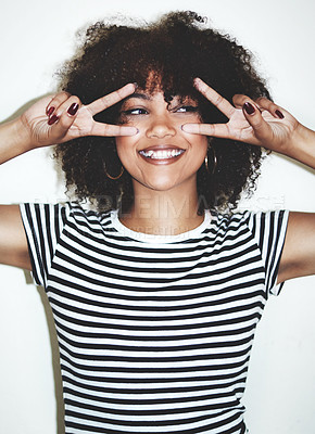 Buy stock photo Studio shot of a playful young woman showing the peace sign against a gray background
