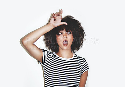 Buy stock photo Studio shot of a young woman showing a loser gesture against a gray background