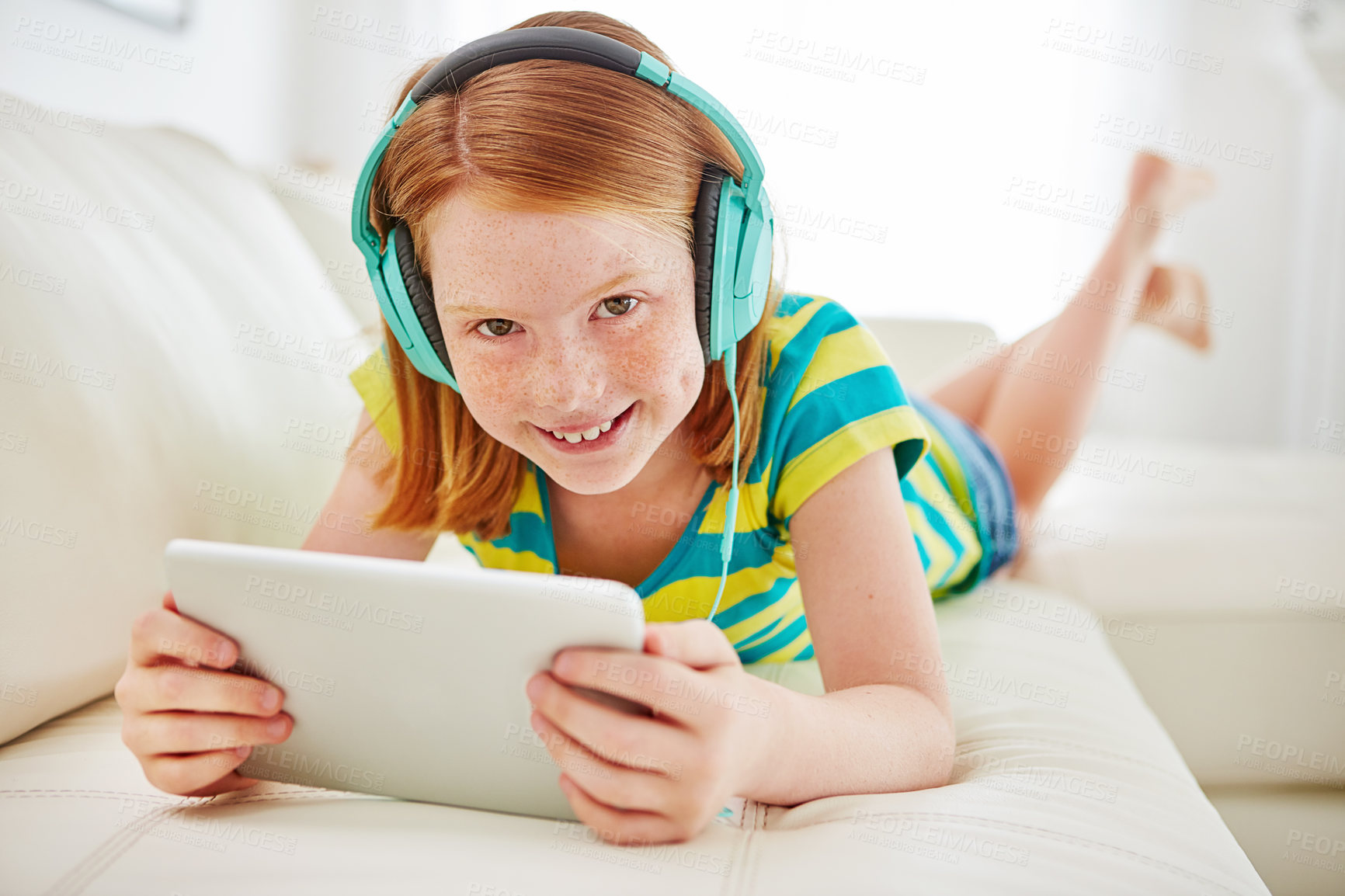 Buy stock photo Shot of a little girl using a digital tablet with headphones at home