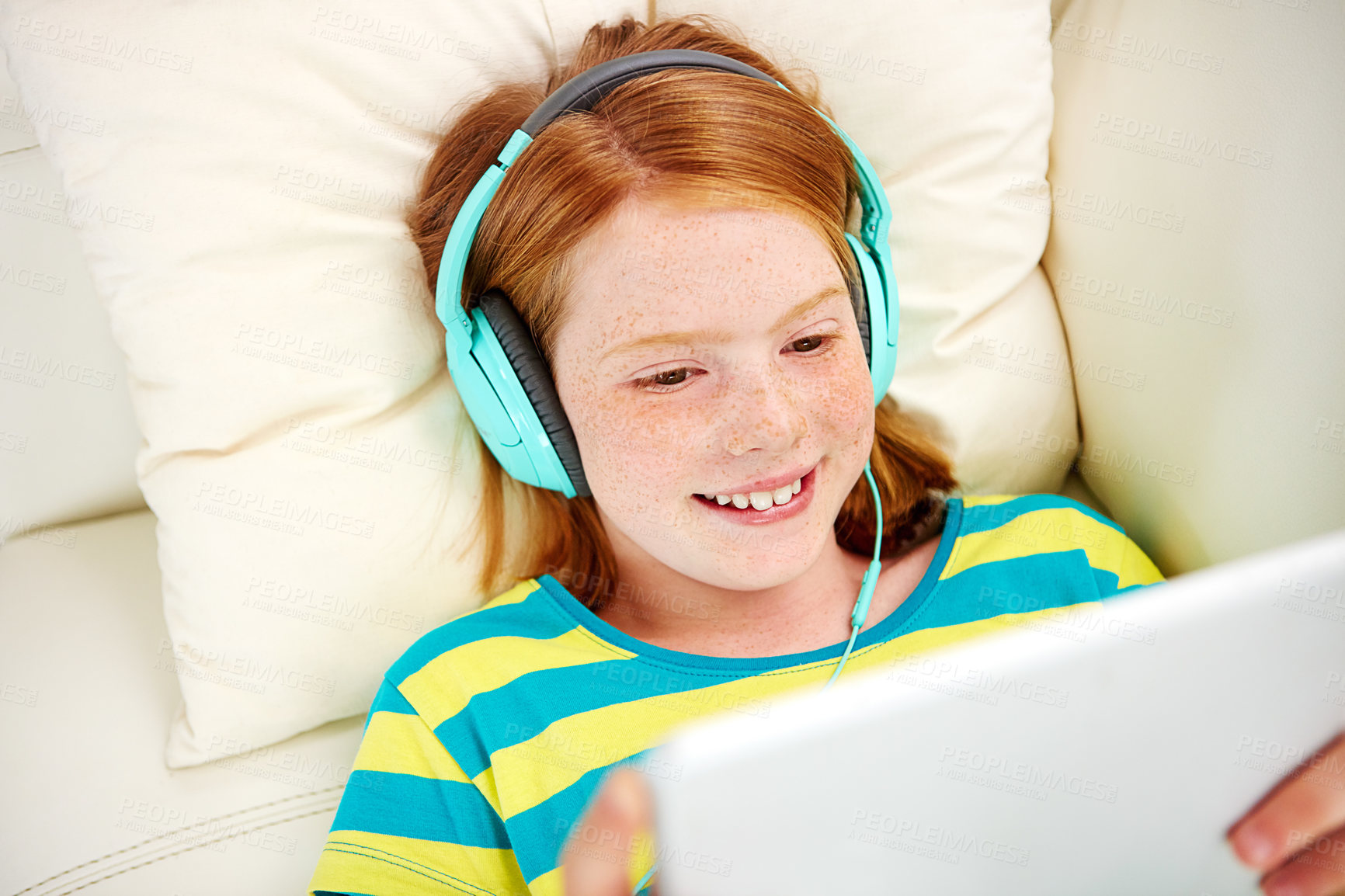 Buy stock photo Shot of a little girl using a digital tablet with headphones at home