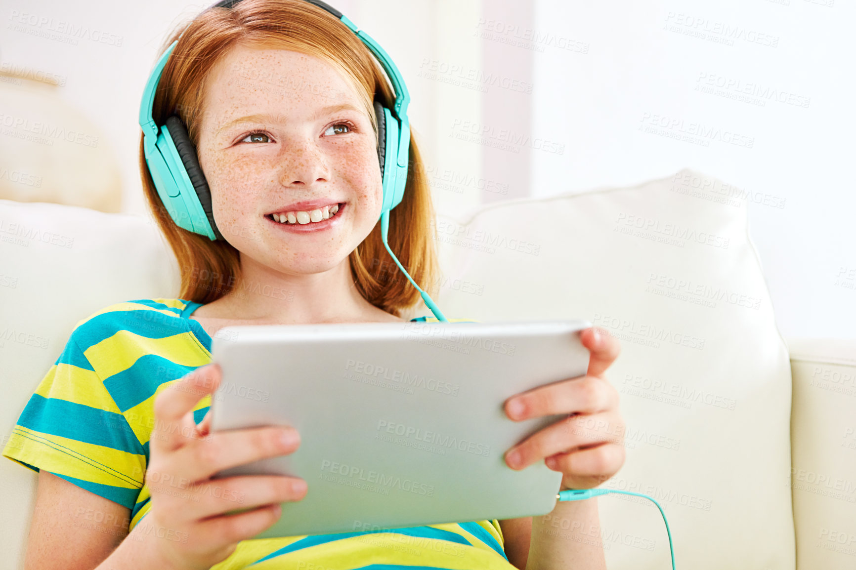 Buy stock photo Shot of a little girl using a digital tablet with headphones at home