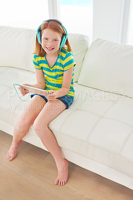 Buy stock photo Shot of a little girl using a digital tablet with headphones at home