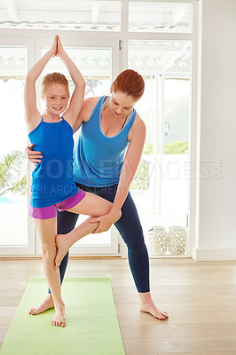 Buy stock photo Shot of a mother and daughter doing yoga together in the living room