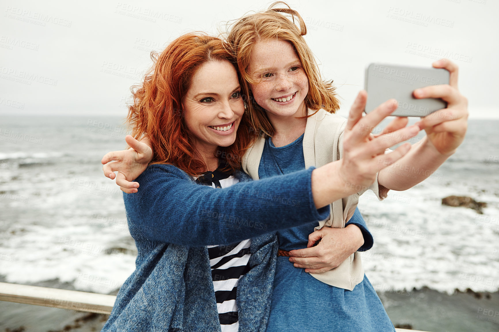 Buy stock photo Shot of a mother and her young daughter taking a selfie at the waterfront