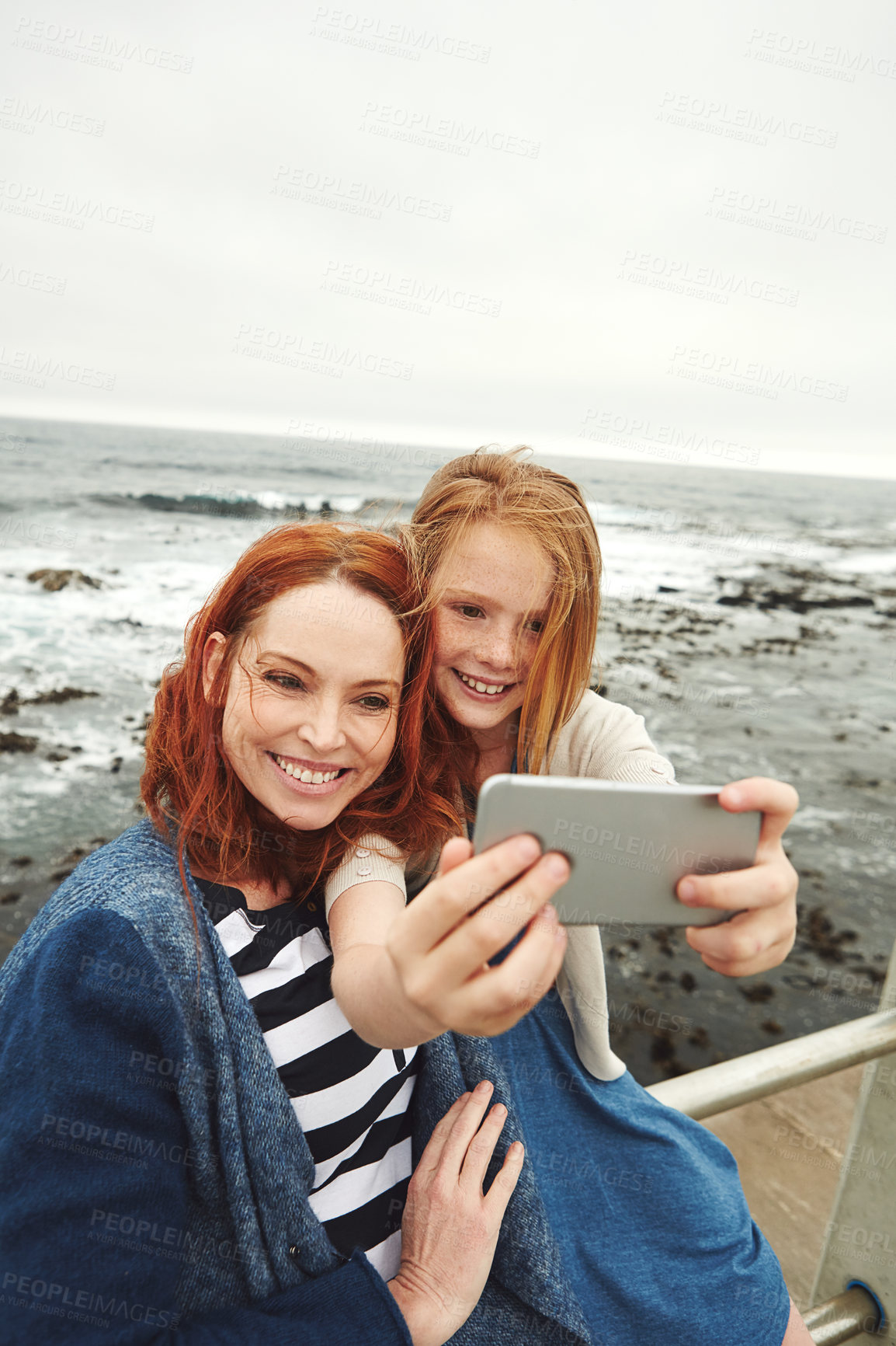 Buy stock photo Shot of a mother and her young daughter taking a selfie at the waterfront