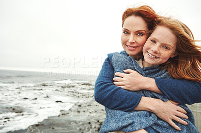 Buy stock photo Shot of a mature woman embracing her young daughter at the waterfront