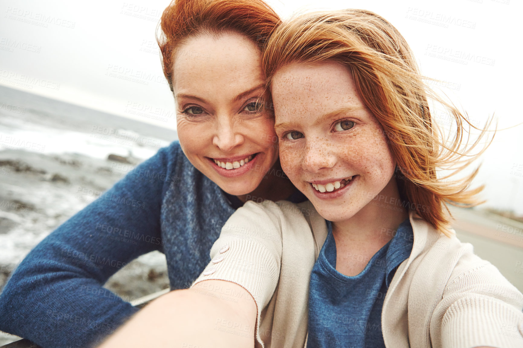 Buy stock photo Shot of a mother and her young daughter taking a selfie at the waterfront