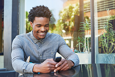 Buy stock photo Shot of a young man using his phone at a sidewalk cafe