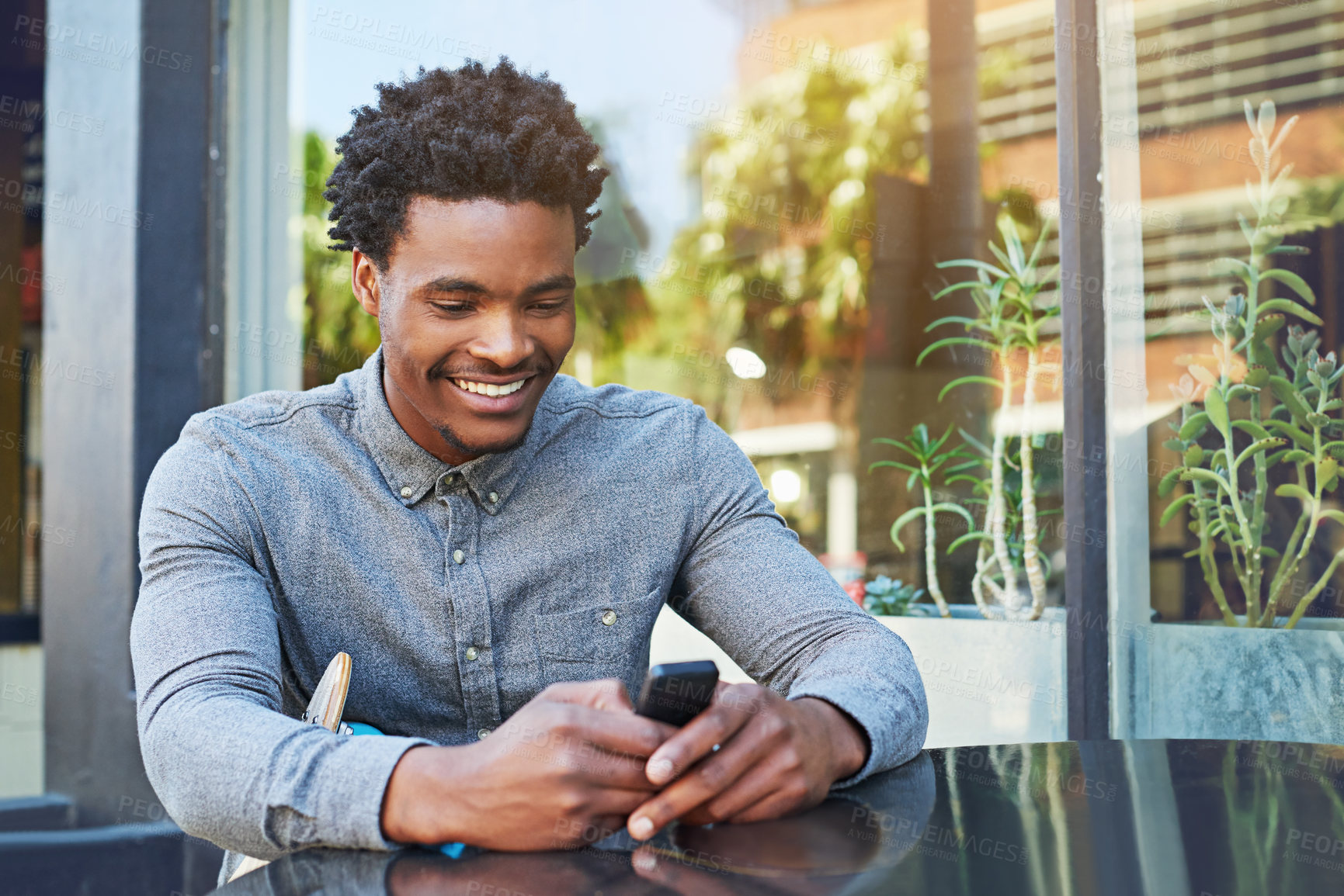 Buy stock photo Shot of a young man using his phone at a sidewalk cafe