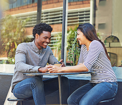 Buy stock photo Happy, interracial couple and bonding with coffee in city for date, chat or funny conversation at outdoor cafe. Man, woman or lovers with smile for talk, social discussion or get together in town