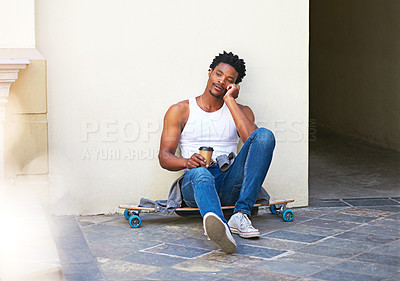 Buy stock photo Shot of a young skater sitting on his skateboard and talking on his cellphone