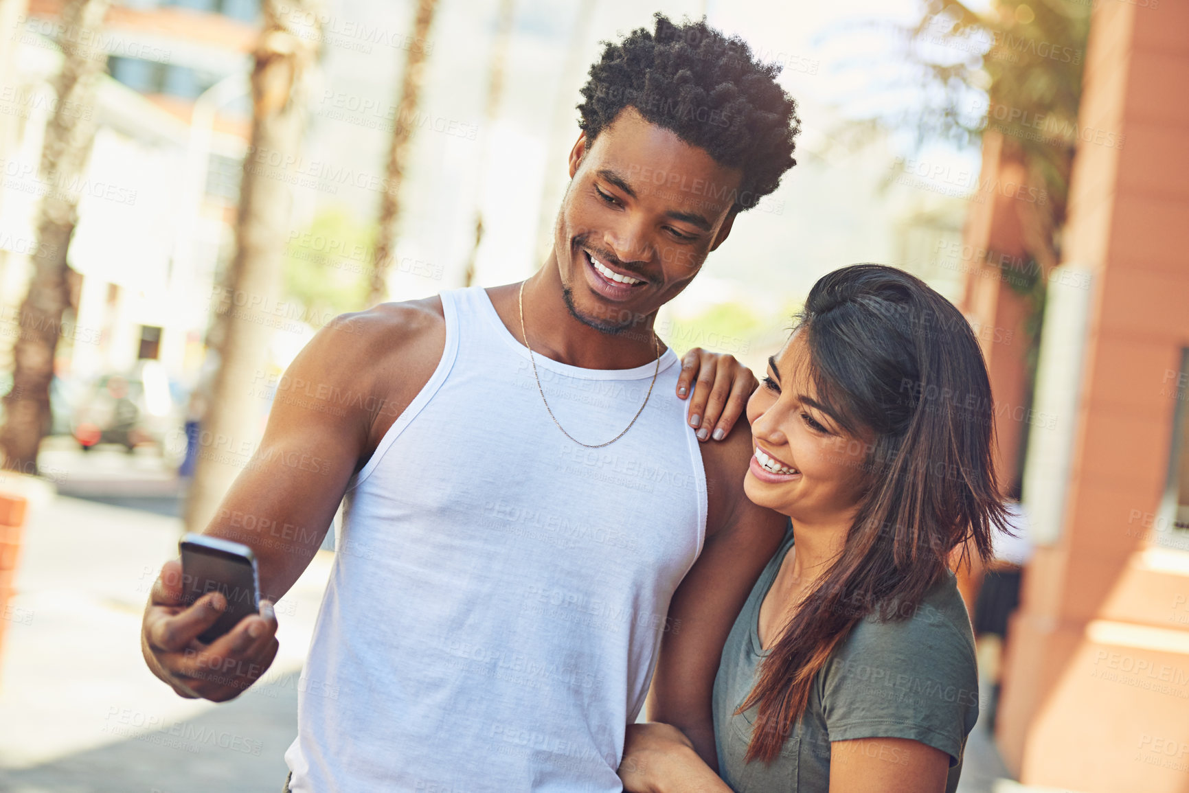 Buy stock photo Shot of a happy young couple using a mobile phone together