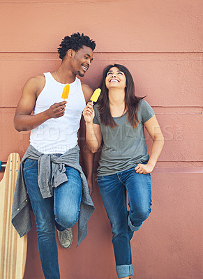 Buy stock photo Shot of a happy young couple eating ice lollies together