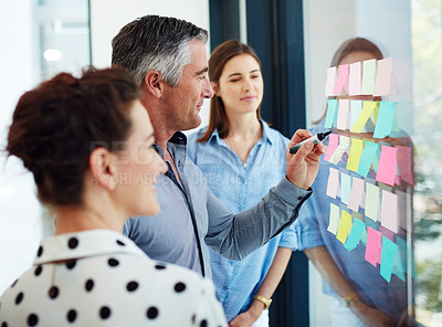 Buy stock photo Cropped shot of three businesspeople working at a whiteboard