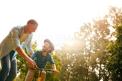 Buy stock photo Shot of a father teaching his son how to ride a bicycle