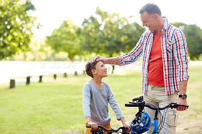 Buy stock photo Shot of a father and son riding bicycles in a park