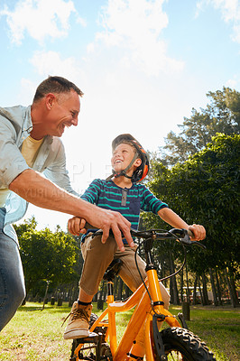 Buy stock photo Shot of a father teaching his son how to ride a bicycle