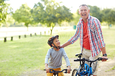 Buy stock photo Portrait of a father and son riding bicycles in a park