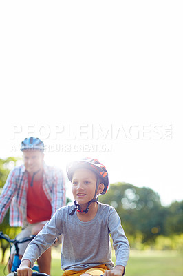 Buy stock photo Shot of a father and son riding bicycles in a park