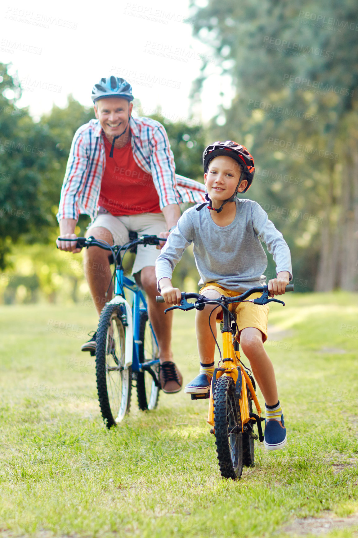Buy stock photo Shot of a father and son riding bicycles in a park