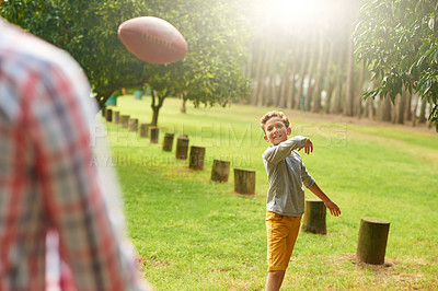 Buy stock photo Shot of a father and son throwing a football in a park