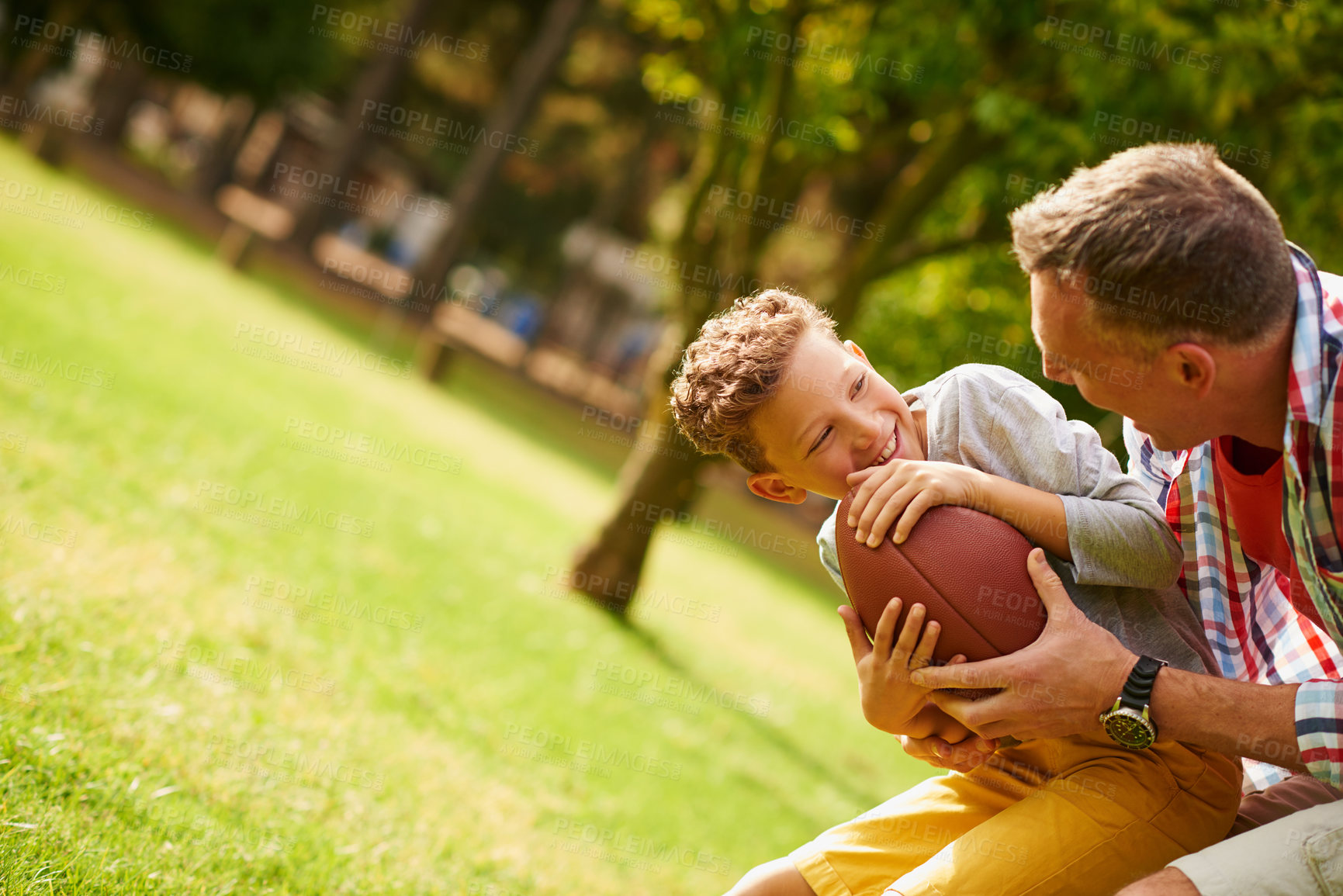 Buy stock photo Shot of a father and son playing football in a park