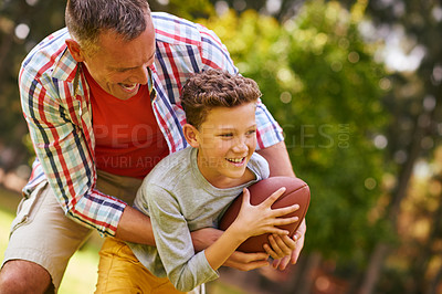 Buy stock photo Shot of a father and son playing football in a park