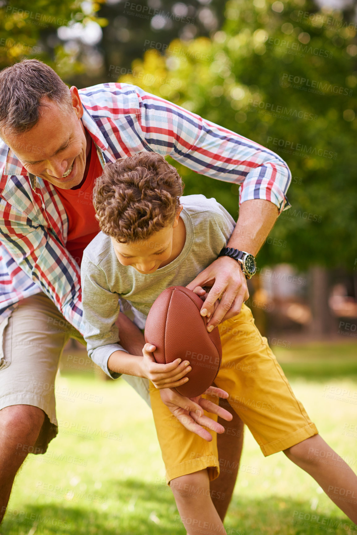 Buy stock photo Shot of a father and son playing football in a park