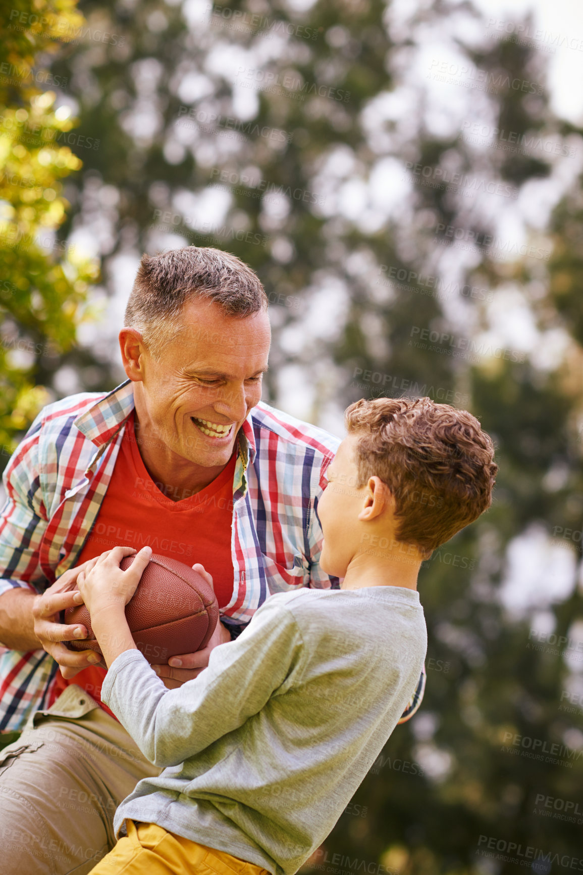 Buy stock photo Shot of a father and son playing football in a park
