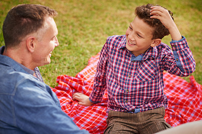 Buy stock photo Shot of a father and son talking together while lying in a park