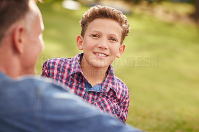 Buy stock photo Portrait of a boy talking with his father while lying in a park