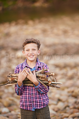 Buy stock photo Portrait of a young boy carrying a bundle of sticks for a fire while camping
