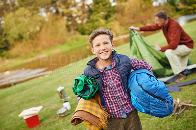 Buy stock photo Portrait of a young boy holding camping gear with his father in the background