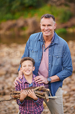 Buy stock photo Portrait of father and his young boy carrying a bundle of sticks for a fire while camping
