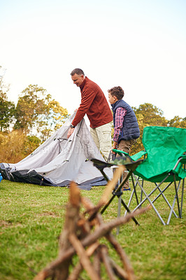 Buy stock photo Shot of a father and son setting up a tent together while camping