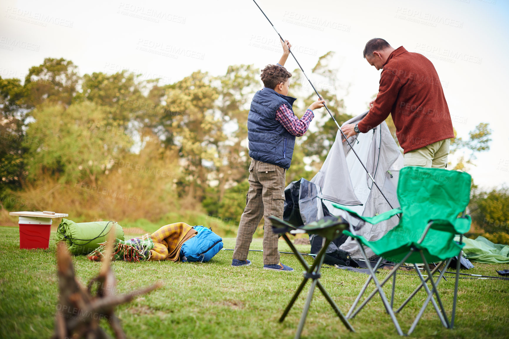 Buy stock photo Shot of a father and son setting up a tent together while camping
