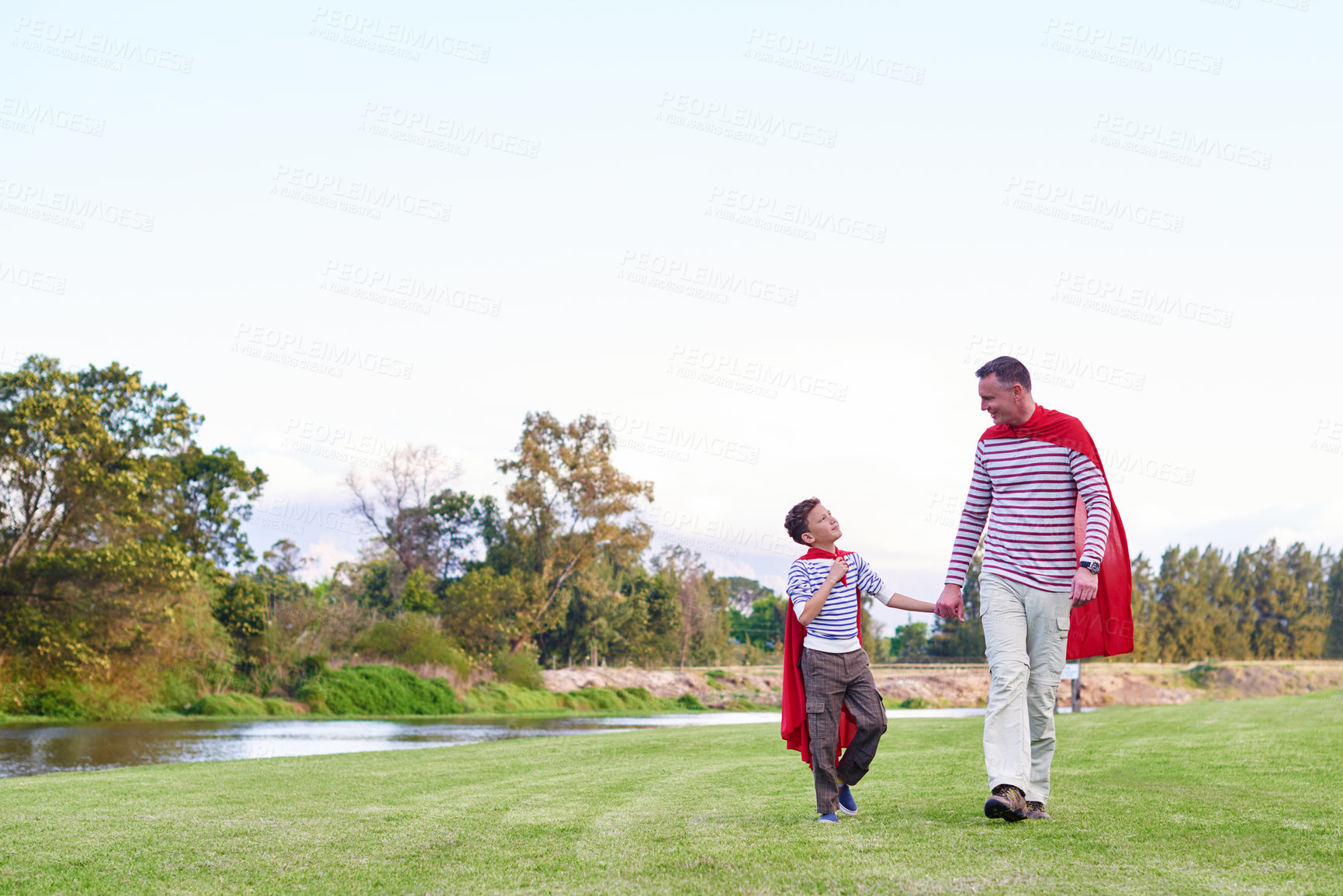 Buy stock photo Shot of a father and his young son pretending to be superheroes while playing outdoors