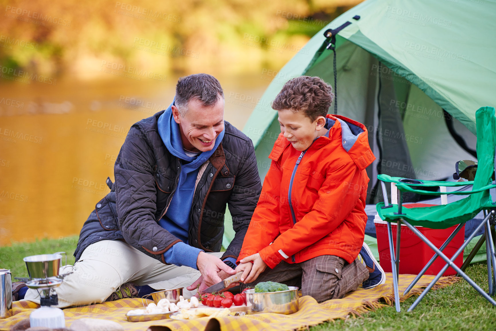 Buy stock photo Shot of a father and son preparing a meal while camping