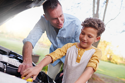 Buy stock photo Shot of a father showing his young son the engine of a car